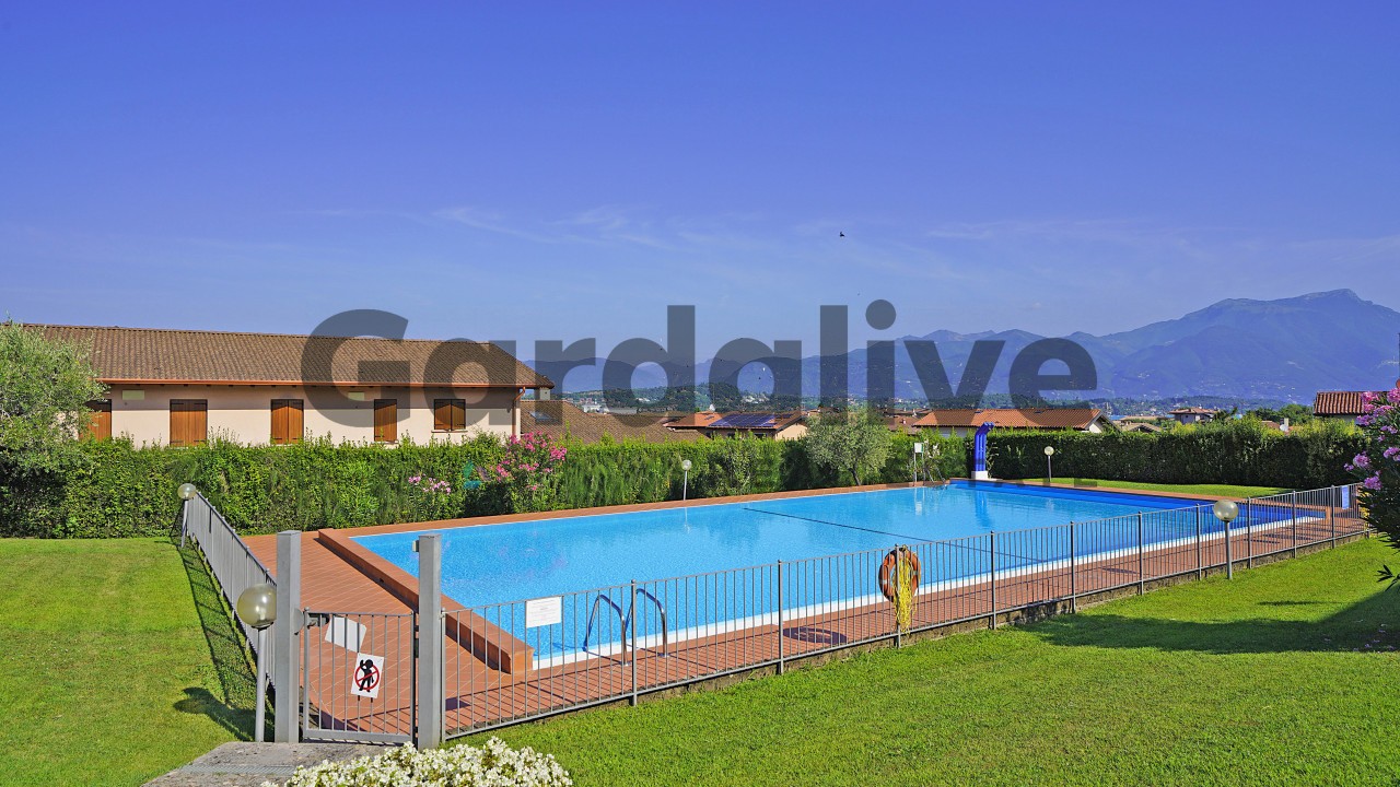 Trilocale con grande terrazzo coperto, vista lago, piscina e box auto
